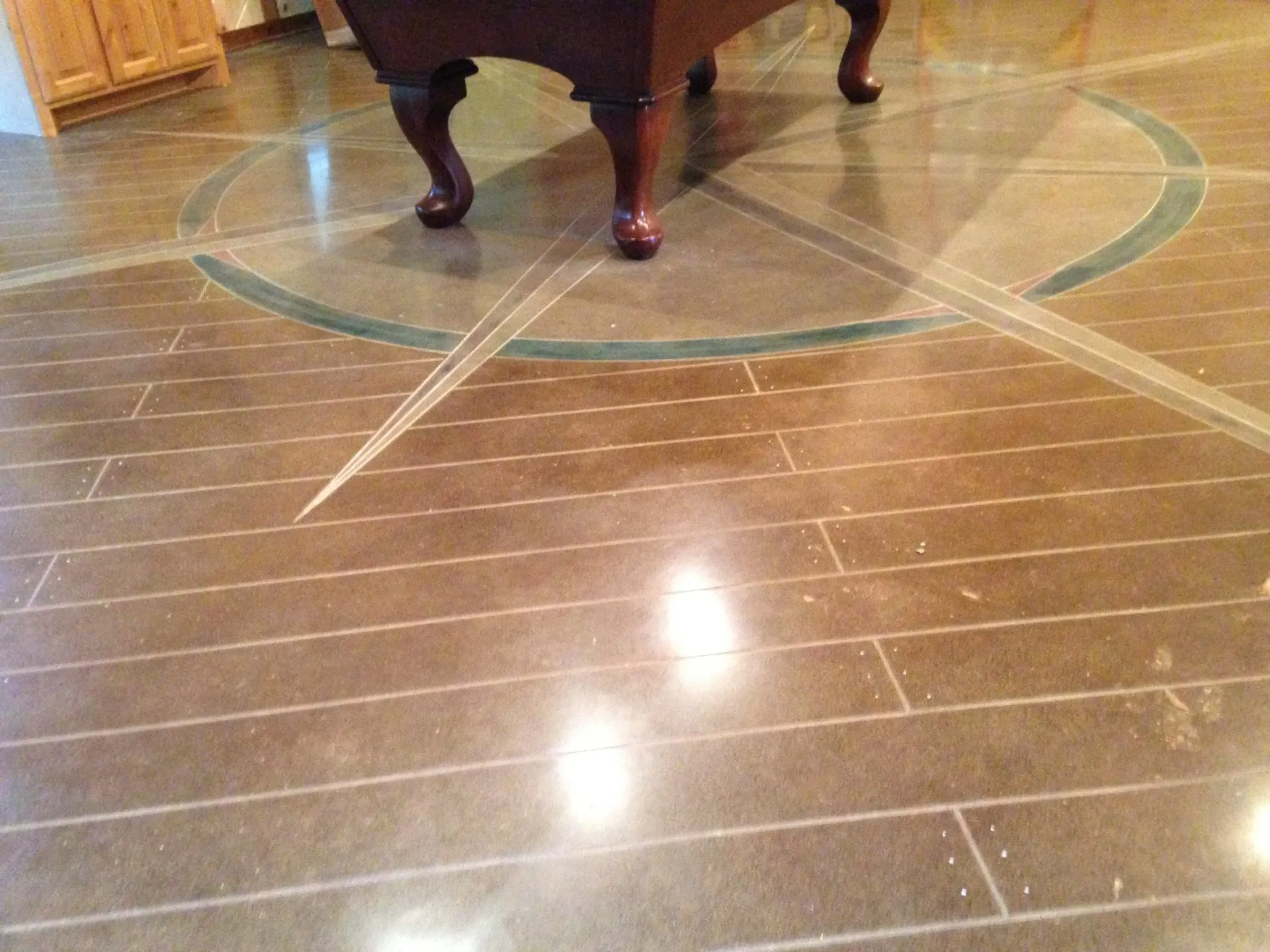 Polished concrete with a compass medallion and plank cuts in a home