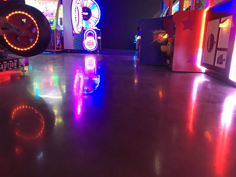 Polished concrete reflecting colorful lights in an arcade