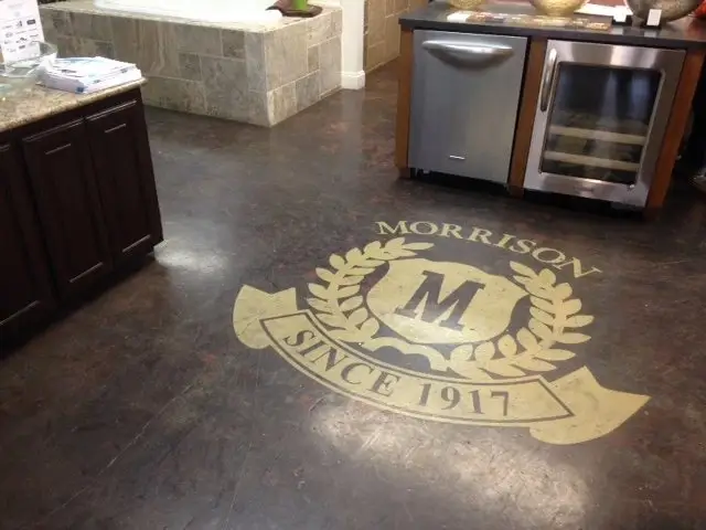 Stained concrete kitchen floor with a custom crest logo