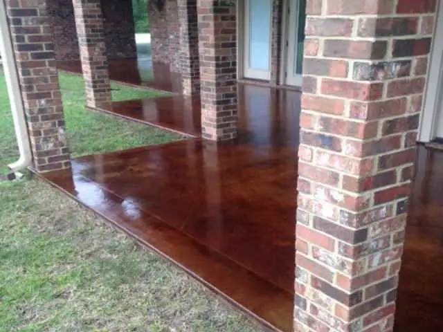 Red-brown stained concrete porch with brick columns