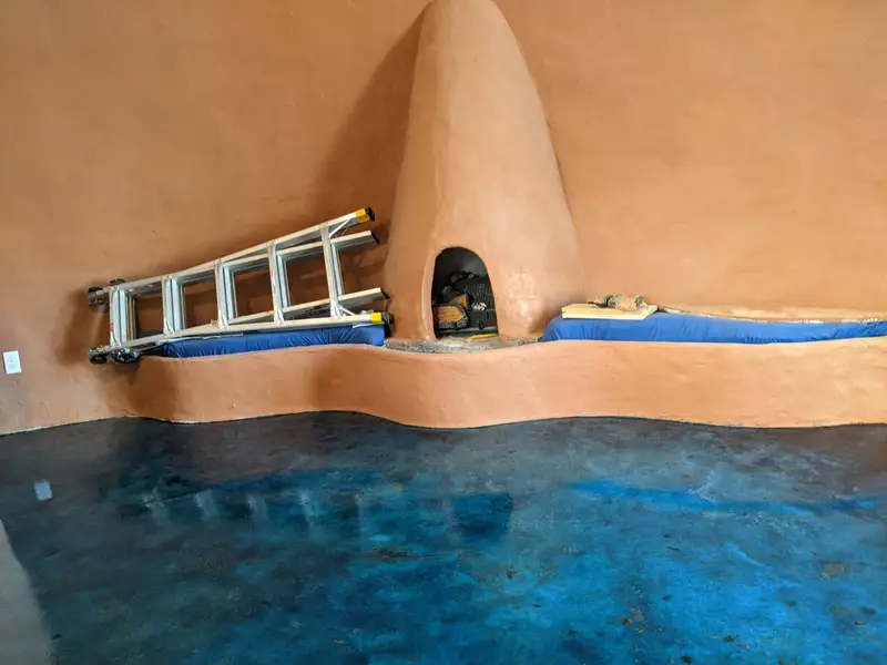 Blue stained concrete beside an adobe-style fireplace