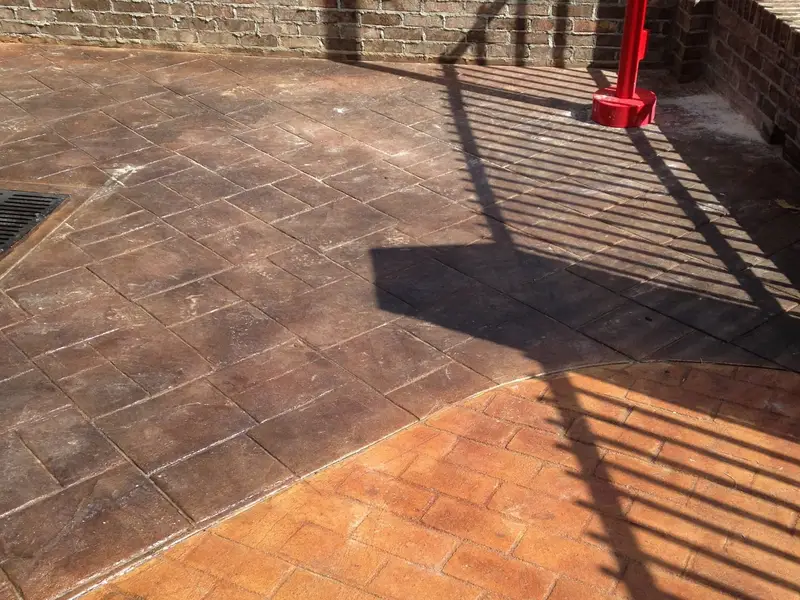 Stamped and stained concrete patio with a brick wall