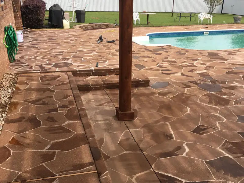 Stained flagstone-pattern concrete patio by a pool