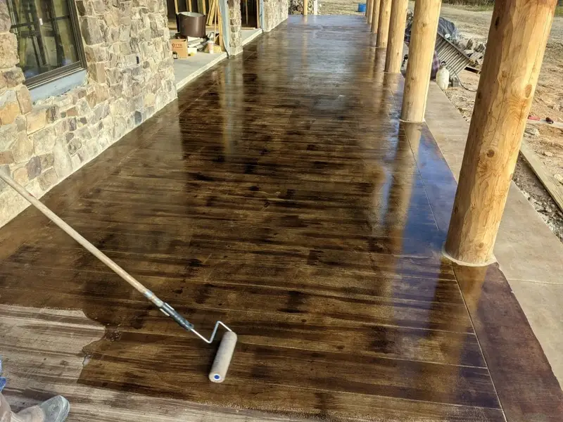 Sealer being rolled onto a wood-look concrete porch